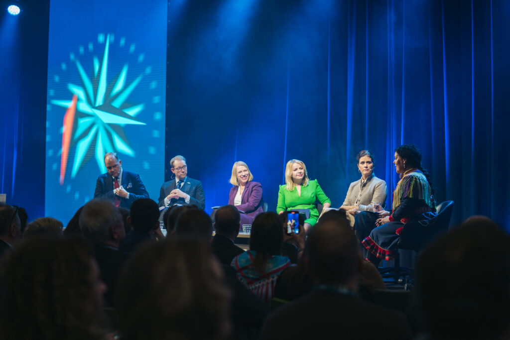 Image shows panel discussion on a stage. 