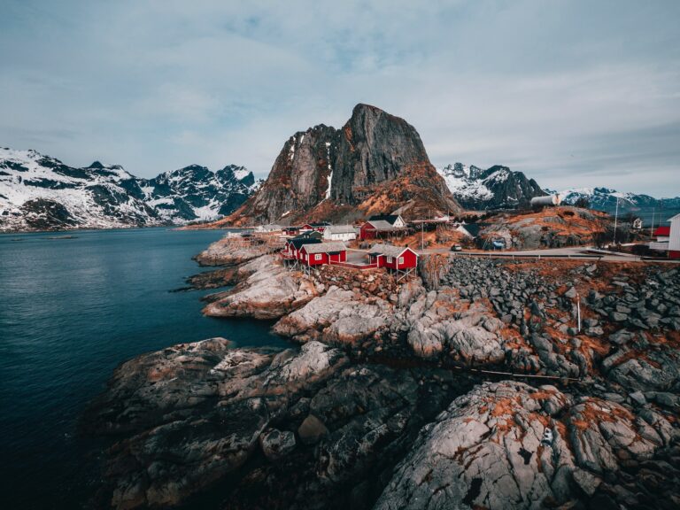 A coastline with a large mountain in the middle and small red houses near the coast.
