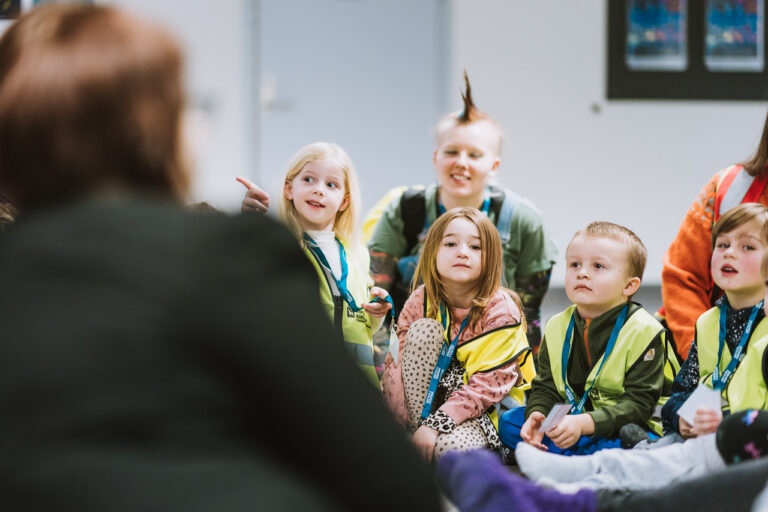 Arctic Frontiers - A group of young children attentively listen to an adult during an indoor Arctic Frontiers - Science for Kids activity or lesson.
