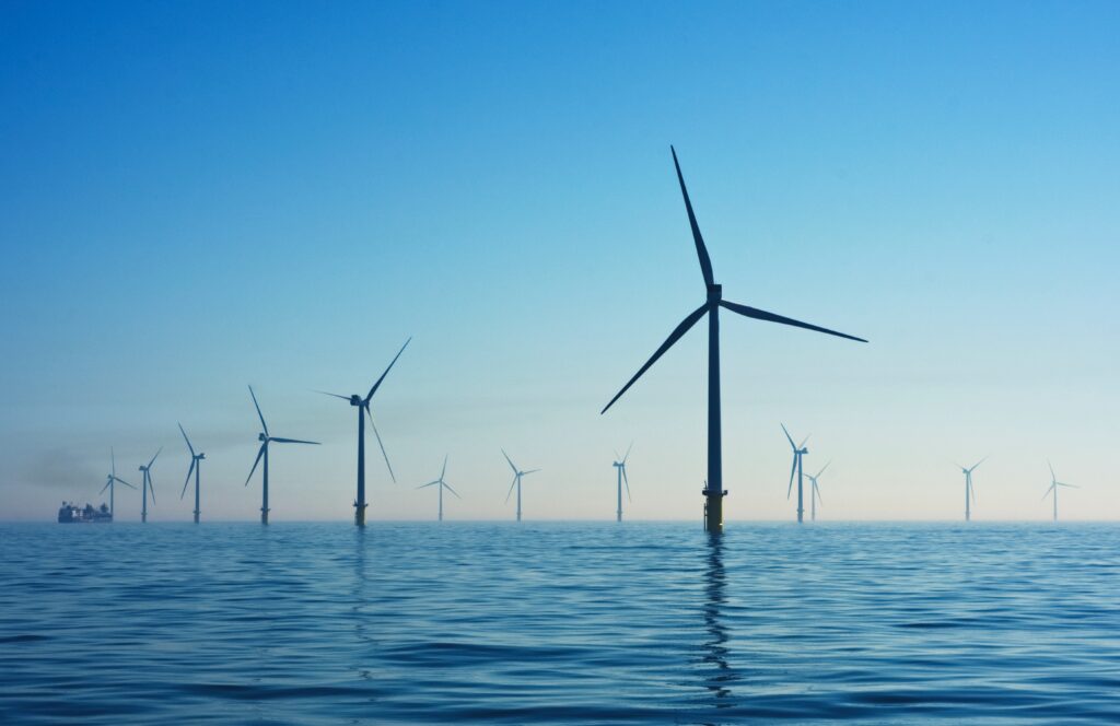 Wind turbines stand out of the ocean. Blue skies and calm seas.