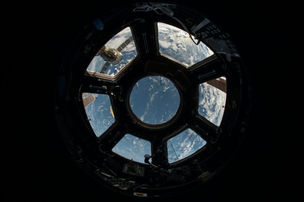 Photo shows image of earth from inside a satellite. 