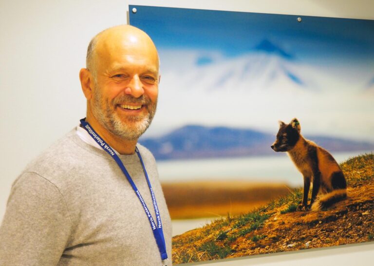 Picture of a man standing in front of a photograph.