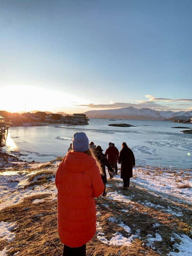 Young people walking down the snow-patched bank on a sunny morning.