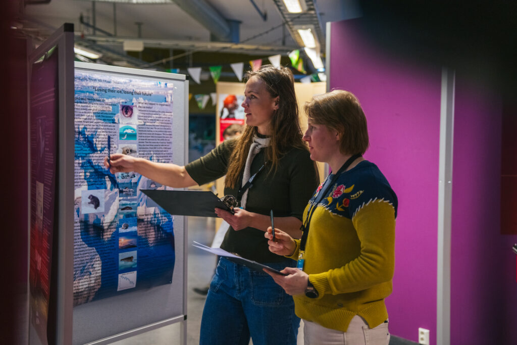 Two women discussing a presentation poster.