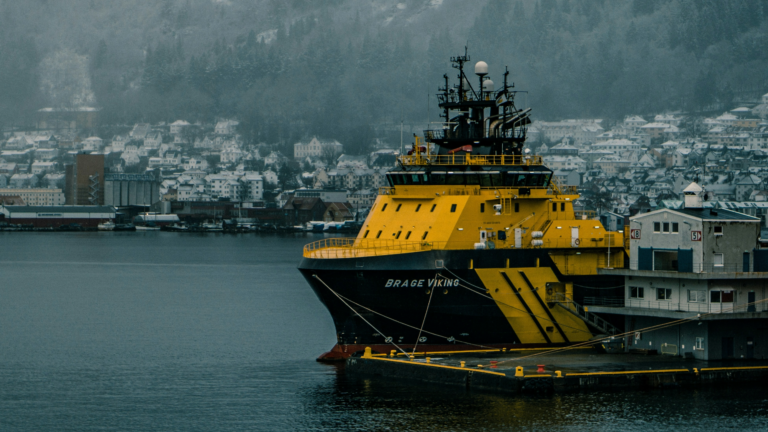 A photo credited to Vitali Harmash, showing a yellow supply vessel in a snow-covered harbor in Bergen.