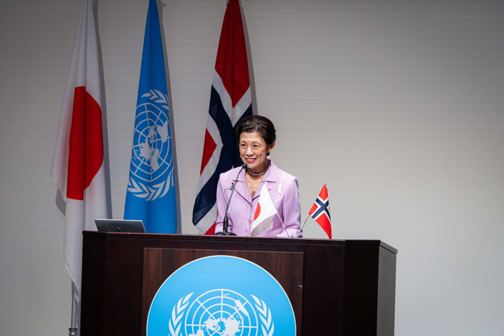 Arctic Frontiers - A woman speaks at a lectern with UN, Japan, and Norway flags, a UN emblem on the lectern, and Tokyo featured as the central location of the event.