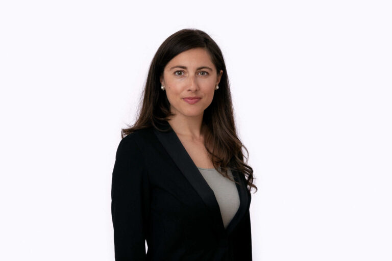 Arctic Frontiers - A woman with long brown hair in a black jacket stands against a plain white background, facing the camera.