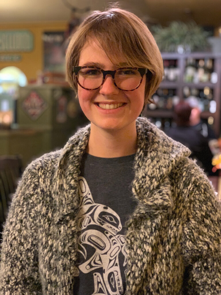 Arctic Frontiers - A smiling person in glasses and a textured jumper, embodying Arctic resilience.