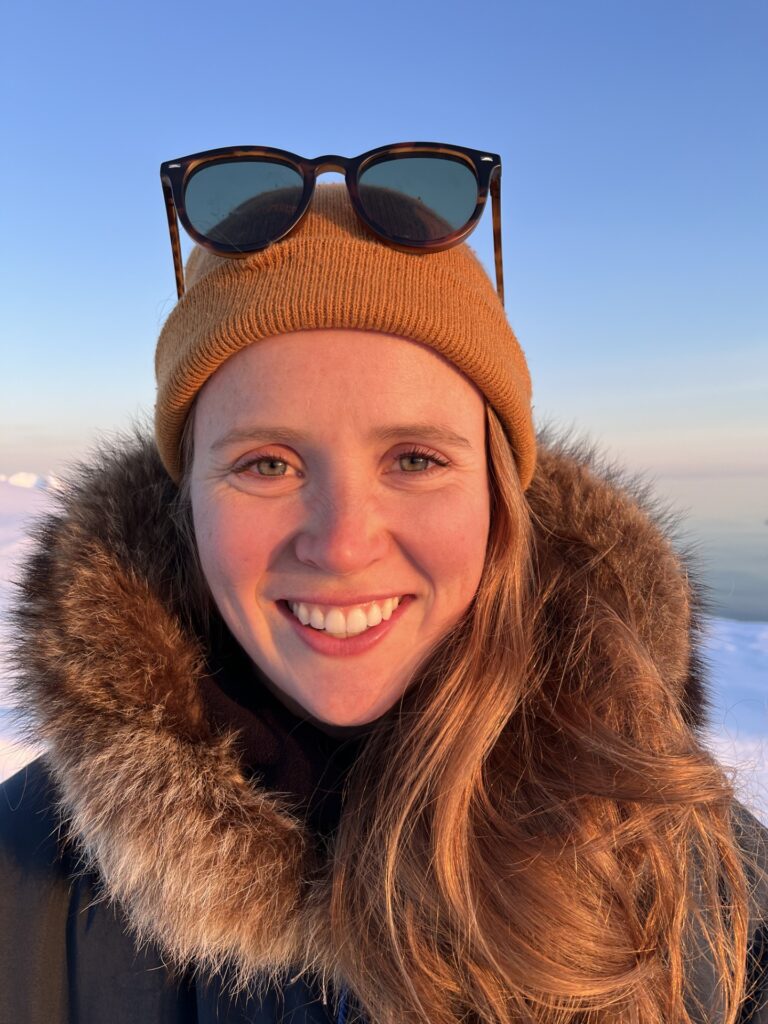 Arctic Frontiers - A woman in a fur-lined parka and tan beanie with sunglasses on her head, embodying a sense of northern resilience.