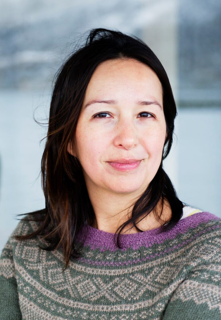 Arctic Frontiers - A smiling woman with dark hair wearing a patterned Arctic knitted jumper.